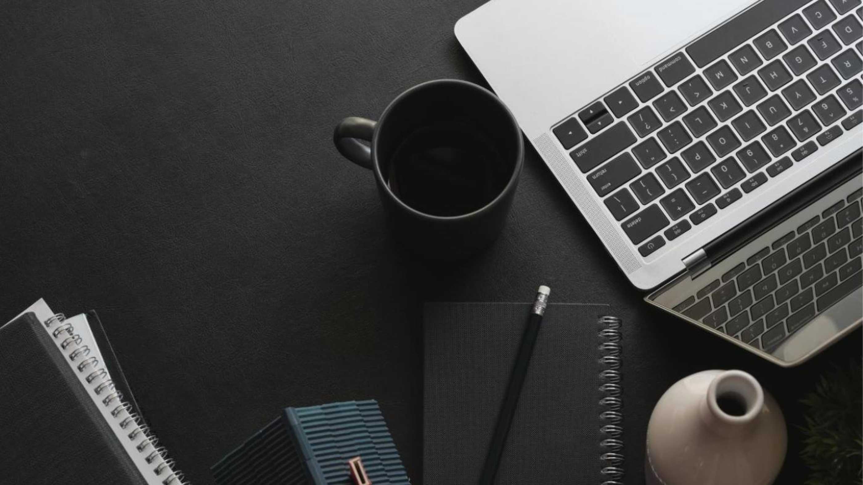 open laptop with coffee cup next to it